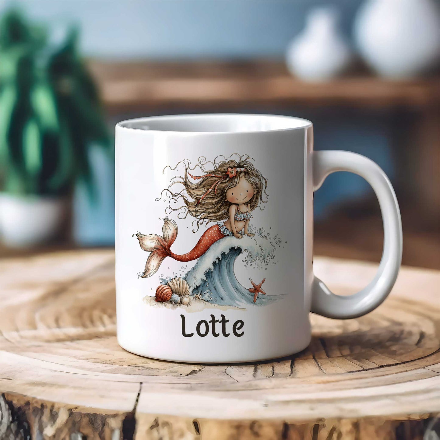 Witte mok met een zeemeermin op een schuimende golf en de naam Lotte op een houten tafel met een onscherpe achtergrond van planten en woondecoratie.