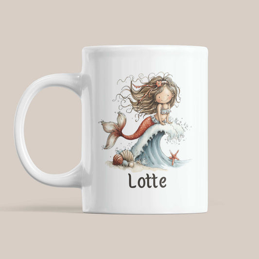Witte mok op een beige achtergrond met een zeemeermin op een golf, een roodkleurige staart, schelpen aan de voet van de golf en de naam Lotte.