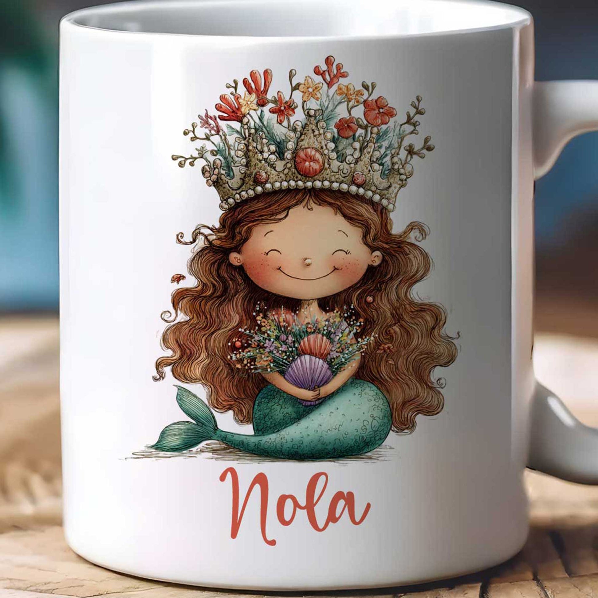 close=up van Witte mok op een beige achtergrond met een zeemeermin met koraalkroon, bloemen en schelpen in haar handen en de naam Nola onder de illustratie.