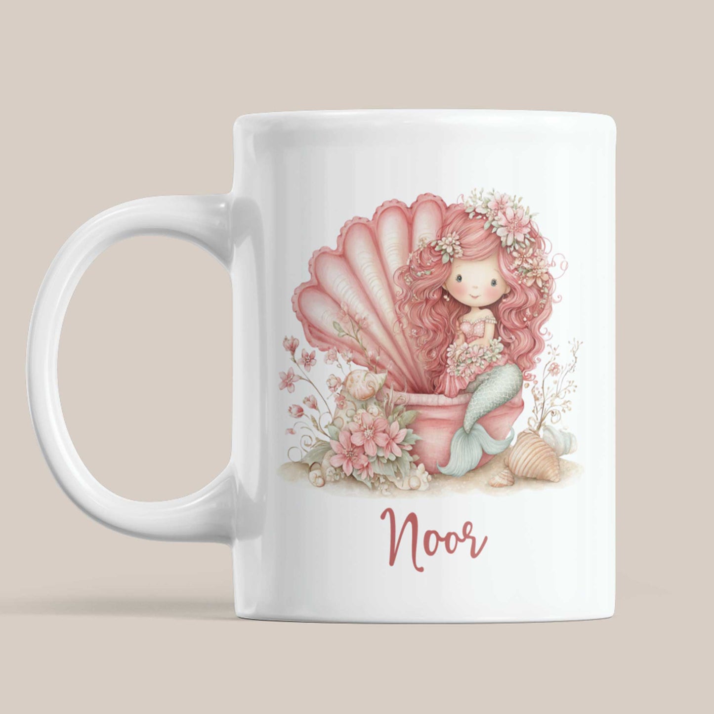 Witte keramische mok met de naam Noor. Op de mok staat een roze zeemeermin met lang krullend haar die in een grote roze schelp zit. Rondom haar staan bloemen, schelpen en zachte pastelaccenten in roze en mintgroene tinten.