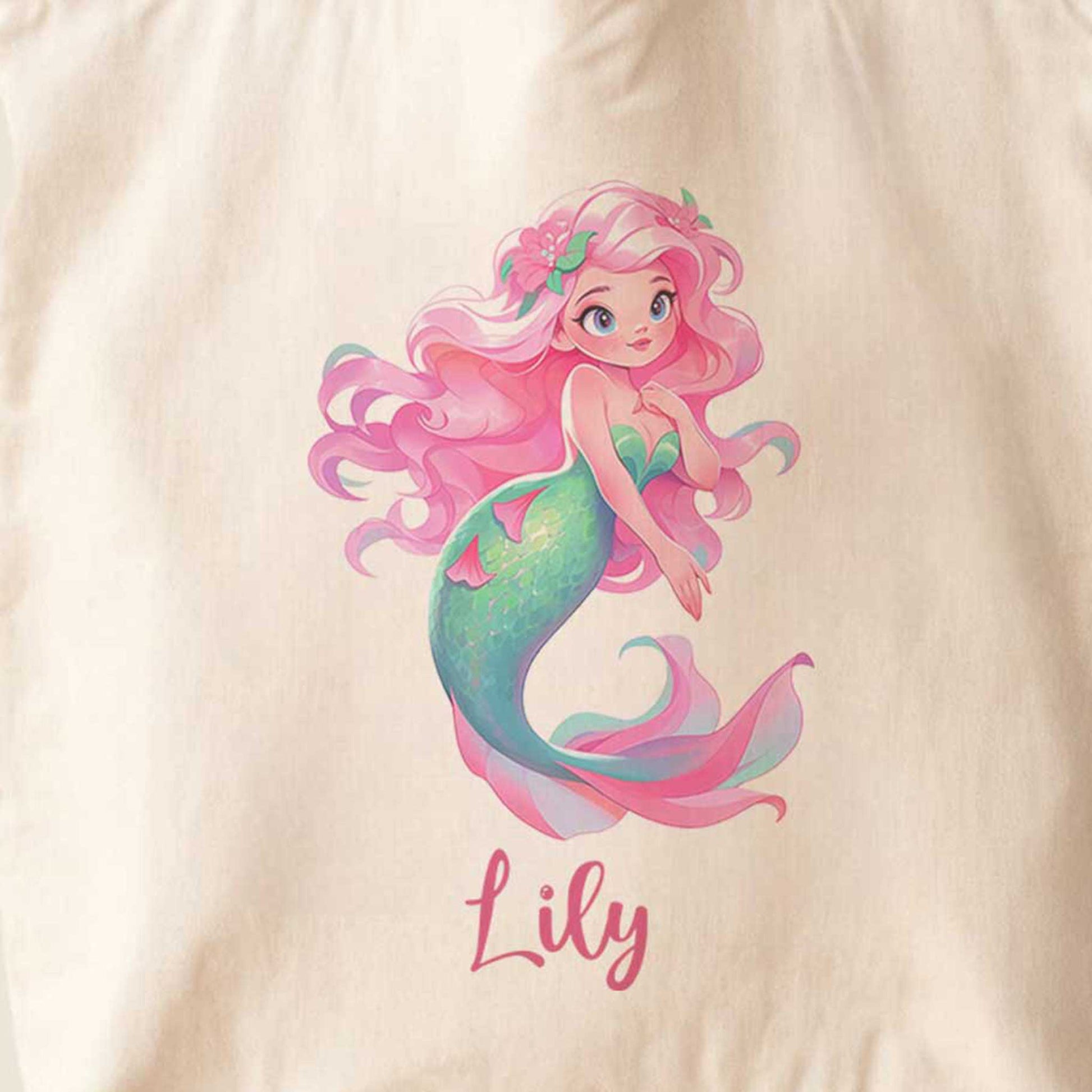 Close-up van een gepersonaliseerde totebag met een kleurrijke zeemeermin. De illustratie toont roze haar met bloemen, een turquoise staart en de naam Lily onder het ontwerp.