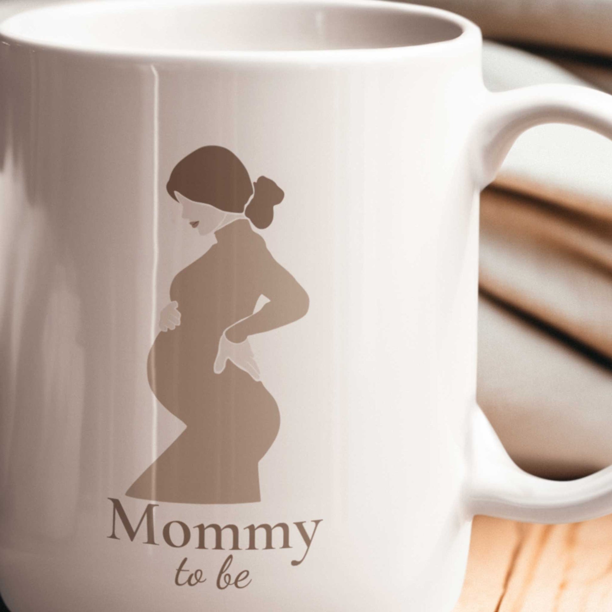 Close-up van een witte Mommy To Be mok met minimalistische illustratie van een zwangere vrouw in neutrale beige tinten.