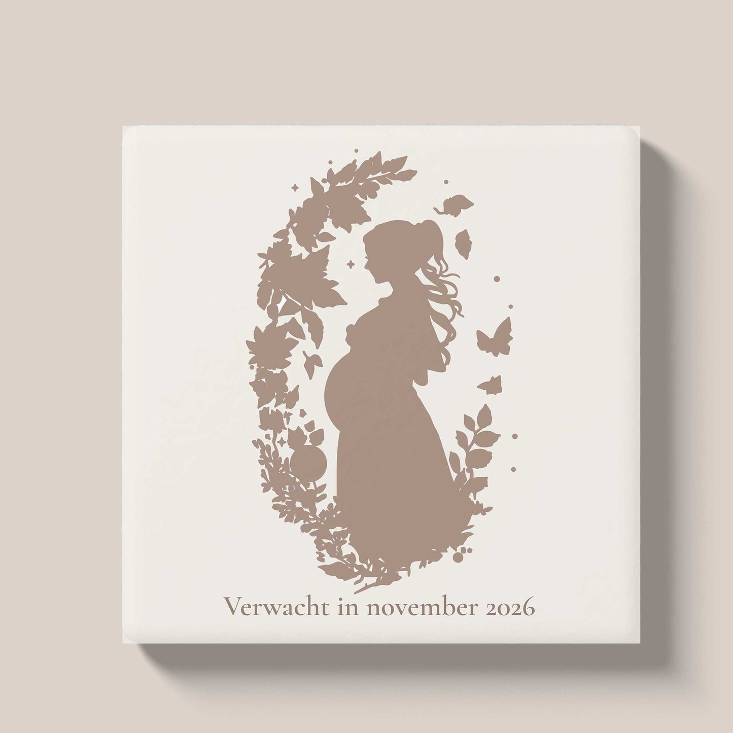 Zwangerschapstegeltje met silhouet van een zwangere vrouw in een bloemenkrans en de tekst 'Verwacht in november 2026' op een lichte achtergrond.